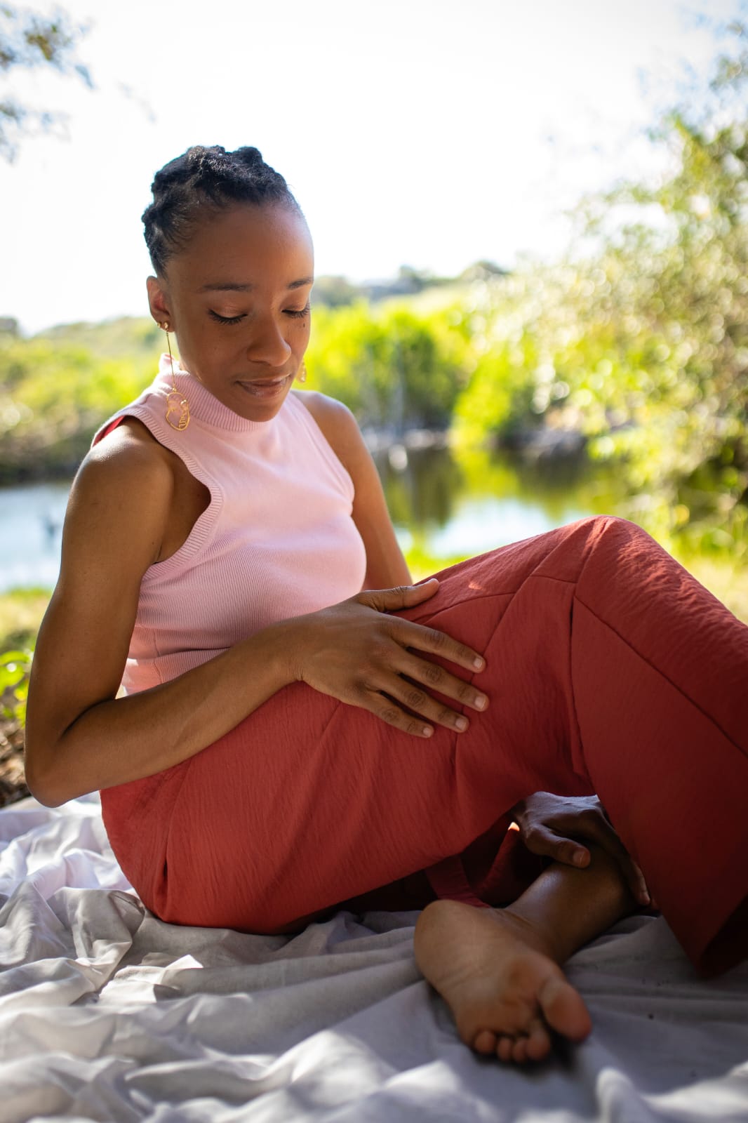 Axelle Célina, infirmière naturopathe en Guadeloupe, pose méditative, forêt tropicale humide et lac en arrière-plan